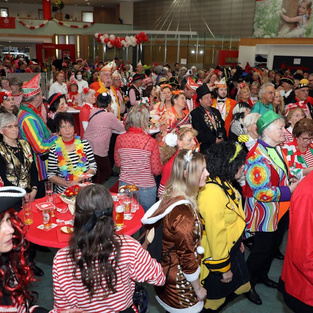 Kostümierte Menschen feiern am Weiberfastnachtstag 2023 in einer Halle Karneval.