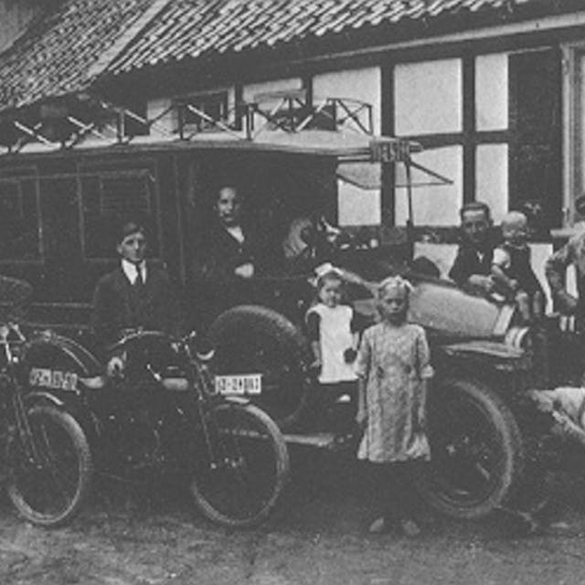 Ein schwarz-weiß Bild zeigt einen alten Bus und einen Teil der Familie Wiedenhoff.