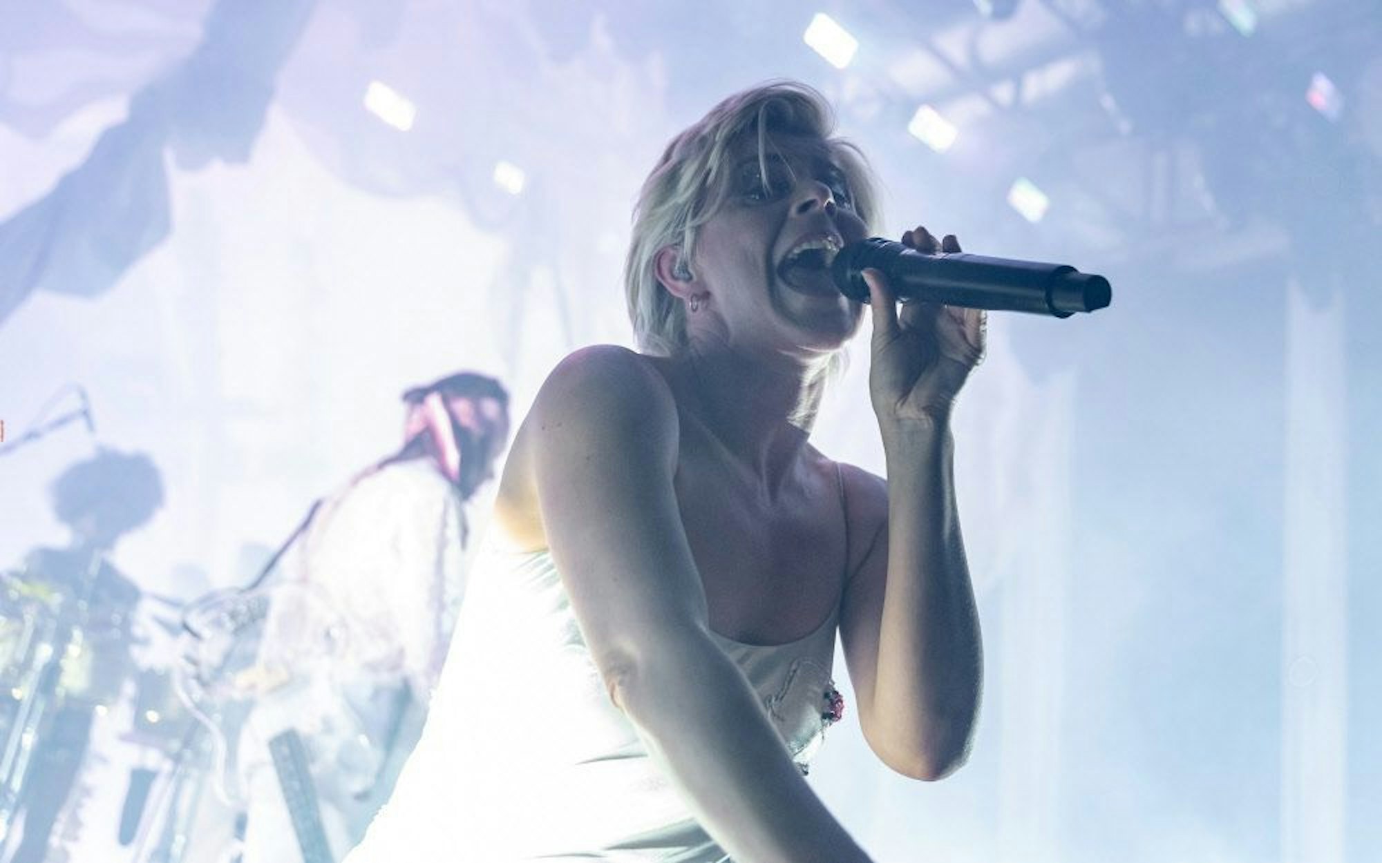 Die schwedische Sängerin Robyn im Jahr 2019 auf der Bühne des Kölner Palladiums. Sie trägt ein silbernes Negligé und singt in ein Mikrofon.