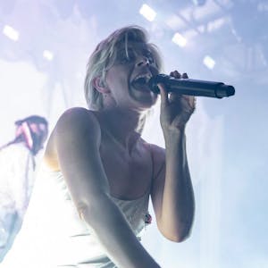 Die schwedische Sängerin Robyn im Jahr 2019 auf der Bühne des Kölner Palladiums. Sie trägt ein silbernes Negligé und singt in ein Mikrofon.