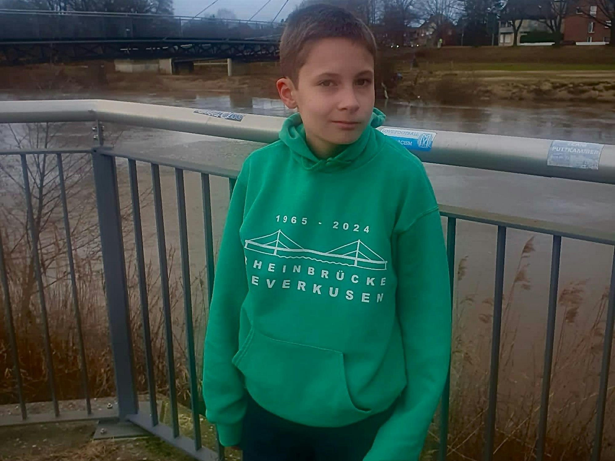 Der zwölfjährige Connor steht mit seinem Pullover, auf dem die Leverkusener Brücke zu sehen, auf einer Brücke in Meppen.