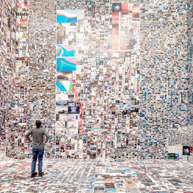 Ein Mann steht in einem mit Millionen Internetfotos tapezierten Raum.