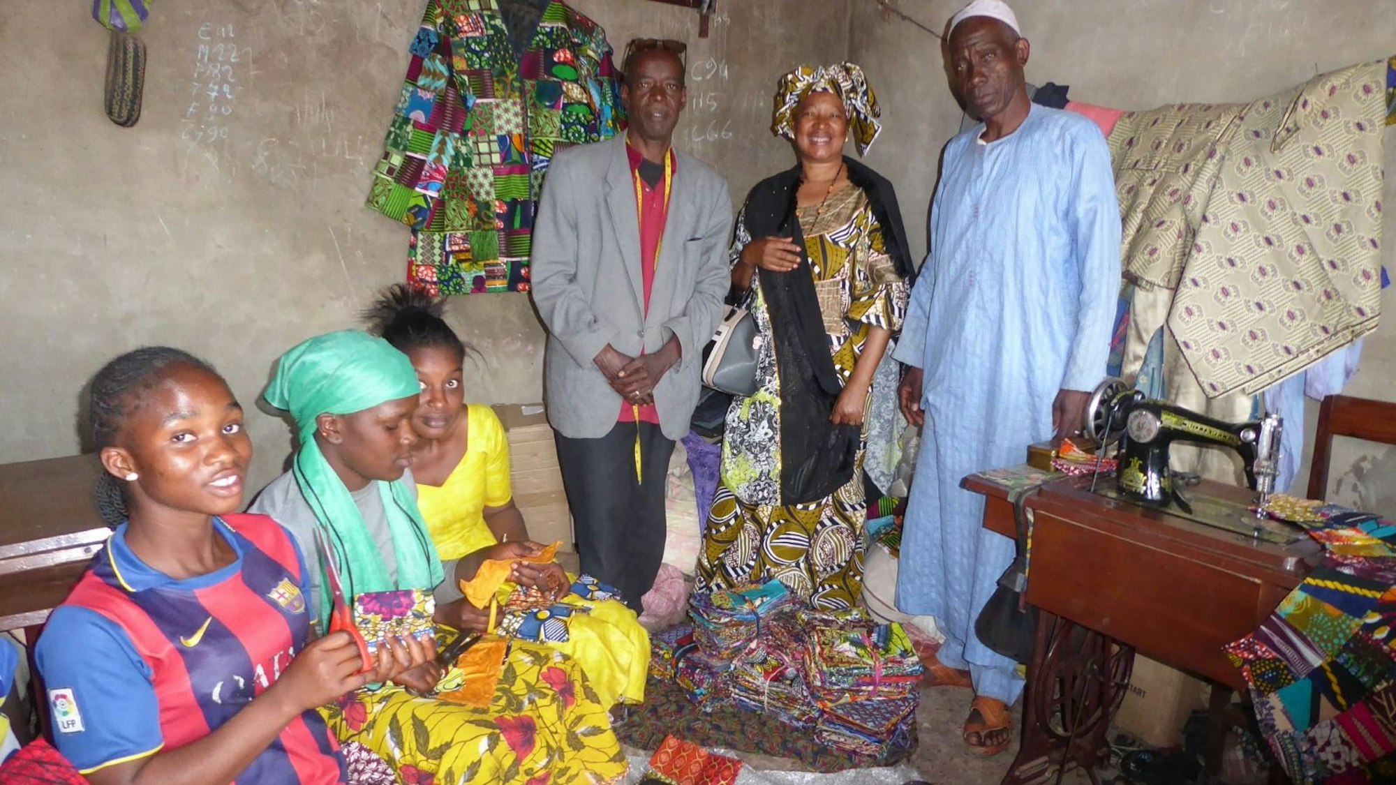 Frauen und Männer in Guinea nähen Lappenclown-Kostüme.