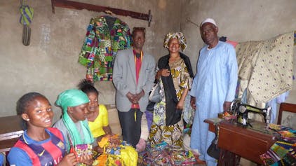 Frauen und Männer in Guinea nähen Lappenclown-Kostüme.