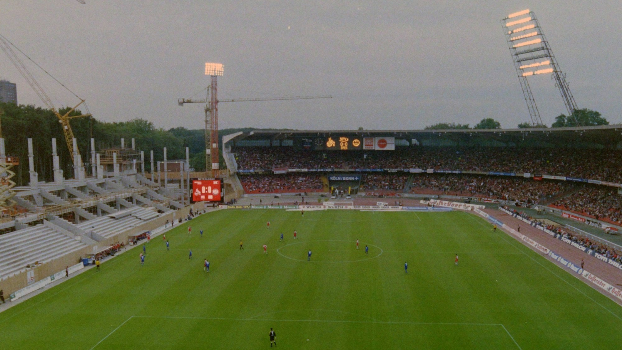 Links im Bild ist der Rohbau der Westtribüne des Rhein-Energie-Stadions. In der Bildmitte bis zum rechten Rand sieht man die noch erhaltenen Reste des Müngersdorfer Stadions.