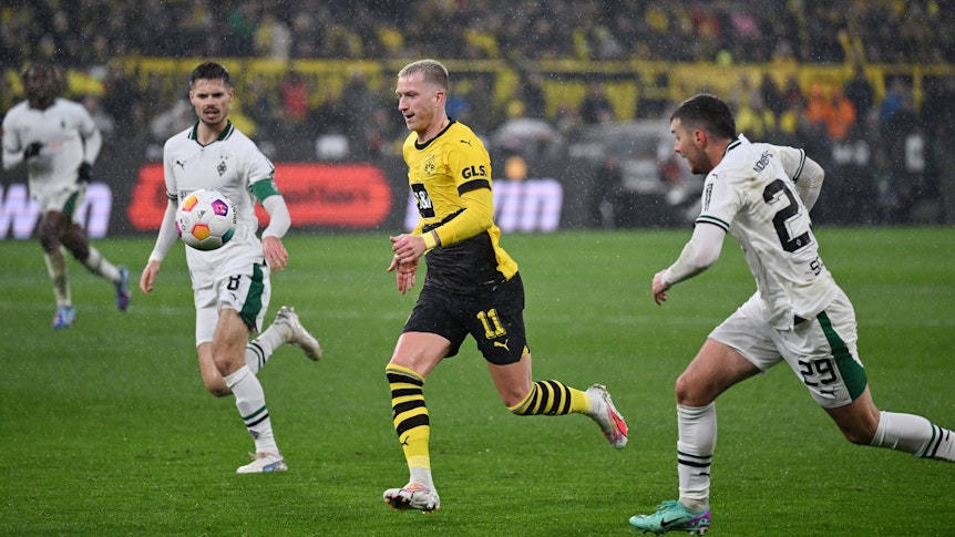 Ein Spieler von Borussia Dortmund setzt sich gegen zwei Spieler von Borussia Mönchengladbach durch.
