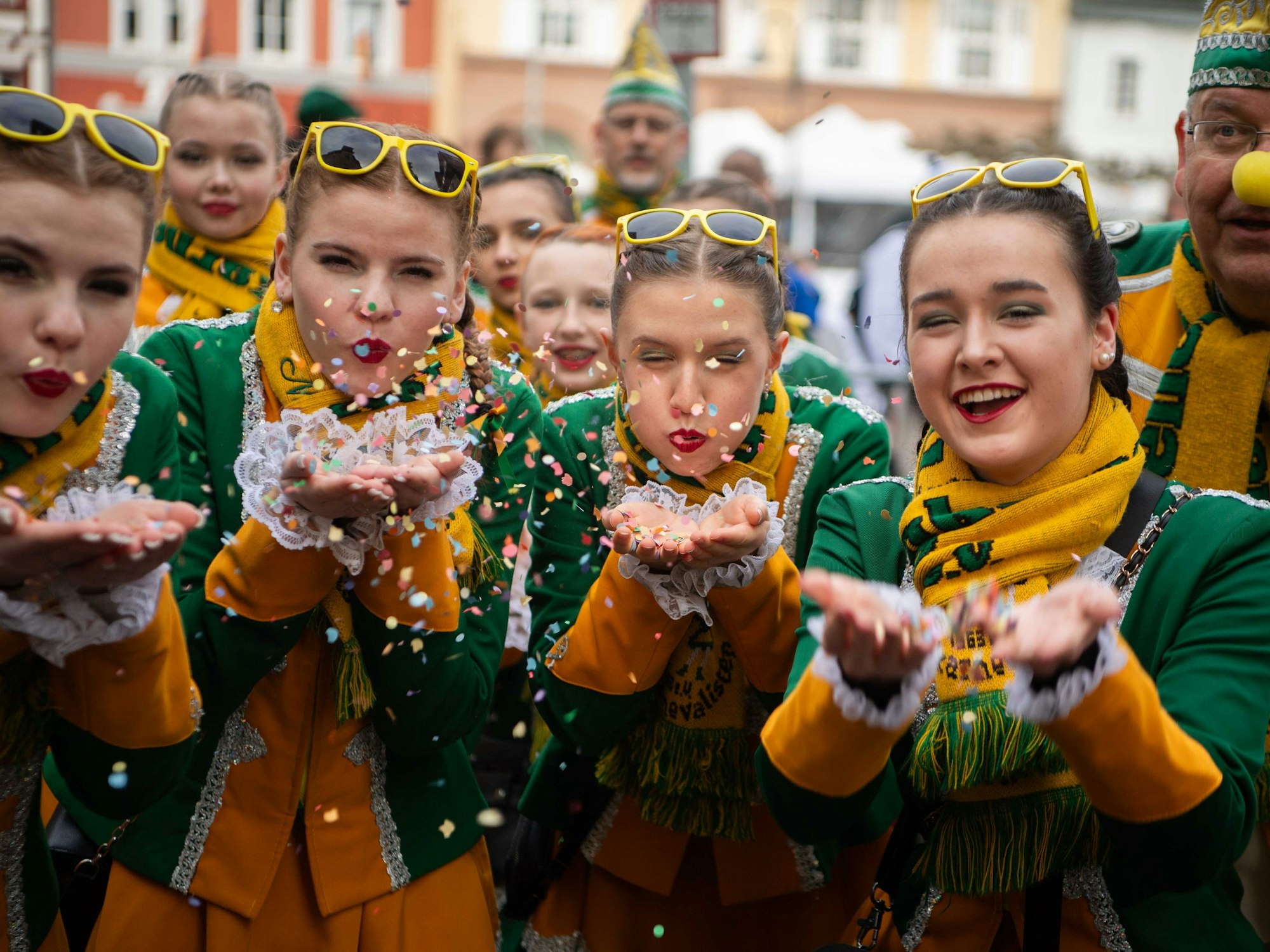 Das Bild zeigt Tänzerinnen der Hovener Jungkarnevalisten, die Konfetti in Richtung der Kamera pusten.