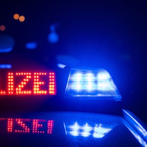 Eine Polizeischrift leuchtet neben einem Blaulicht an einem Abend auf einem Polizeiwagen.