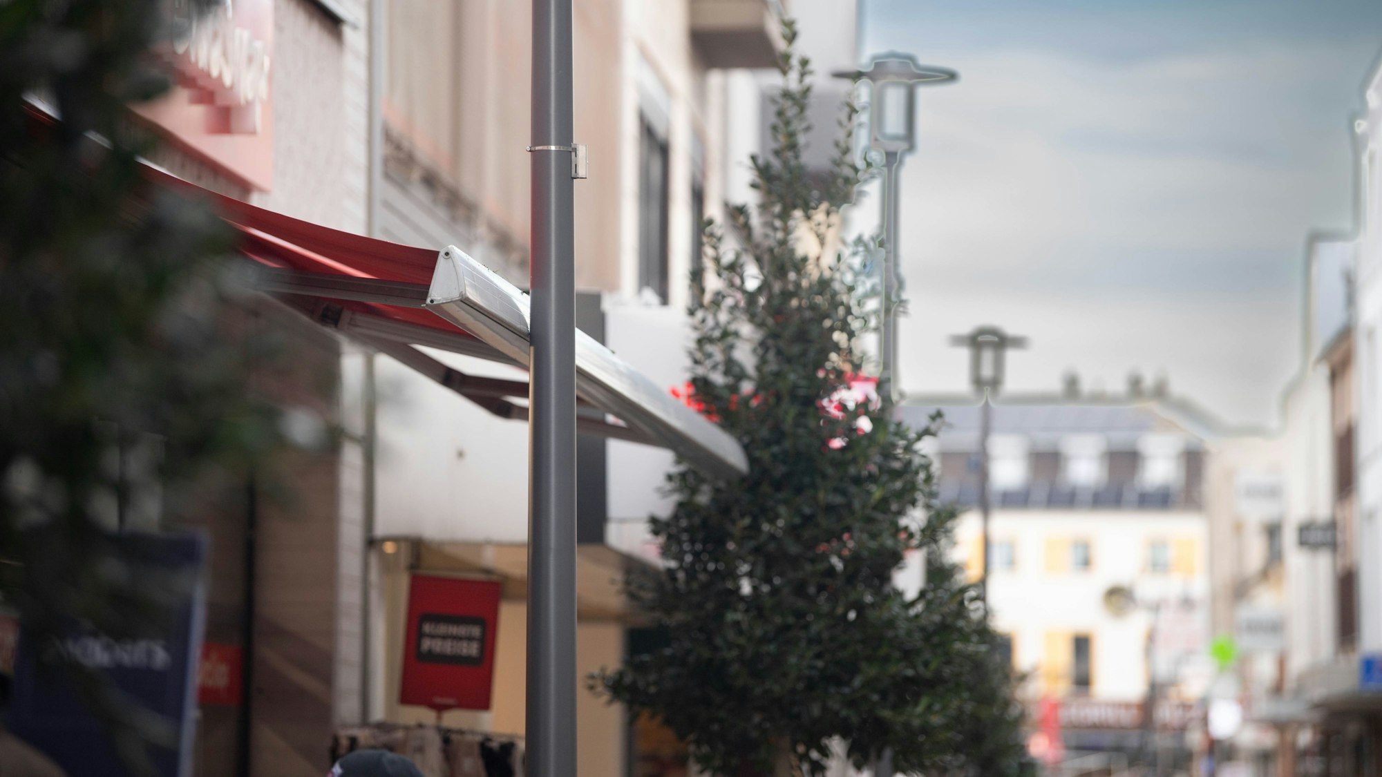 Das Bild zeigt die Markise des Ein-Euro-Shops in der Fußgängerzone. Sie stößt an eine Laterne.