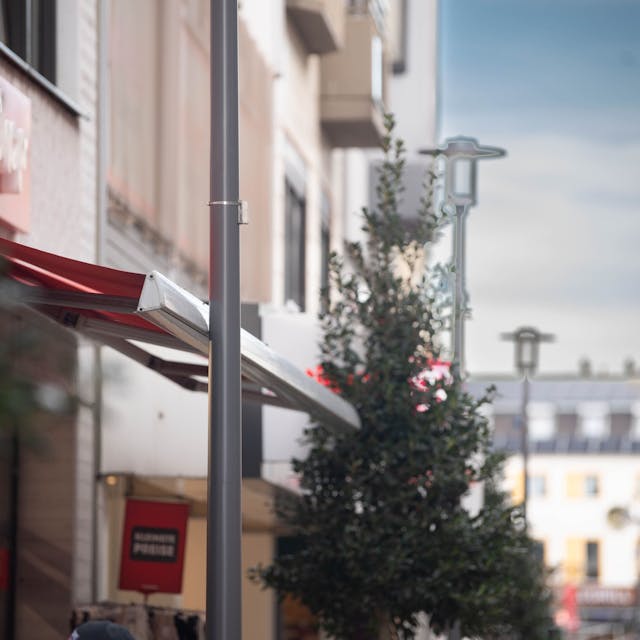 Das Bild zeigt die Markise des Ein-Euro-Shops in der Fußgängerzone. Sie stößt an eine Laterne.