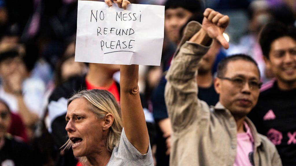 Dieser weibliche Fan beschwerte sich mit einem Zettel für die Abwesenheit von Messi, der Mann hinter hier zeigt den Daumen runter. (Foto: 4. Februar 2024)
