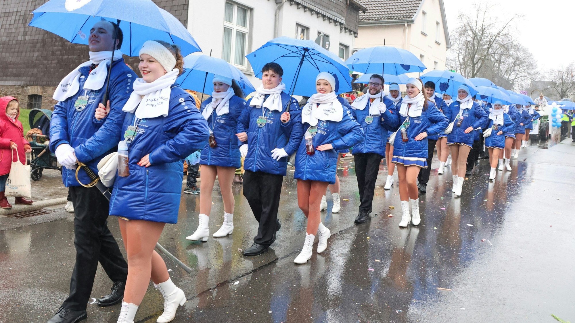 Das Foto zeigt eine Tanzgarde mit blauen Regenschirmen.