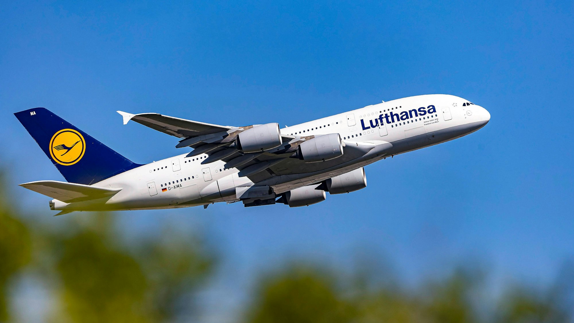Ein Airbus A380 der Lufthansa kurz nach dem Start im Steigflug. Das größte Passagierflugzeug der Welt ist in weiß, blau und gelb lackiert. (Symbolbild)
