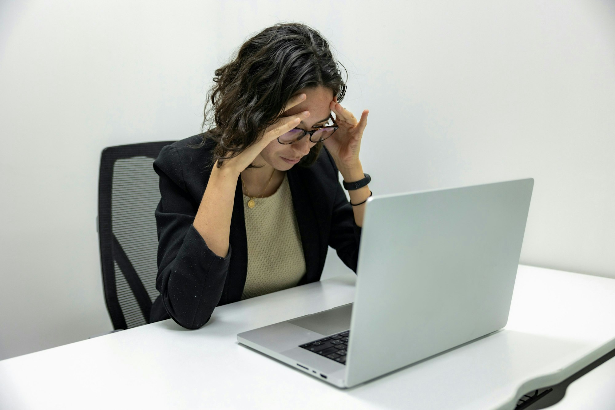 Frau mit Kopfschmerzen am Rechner.