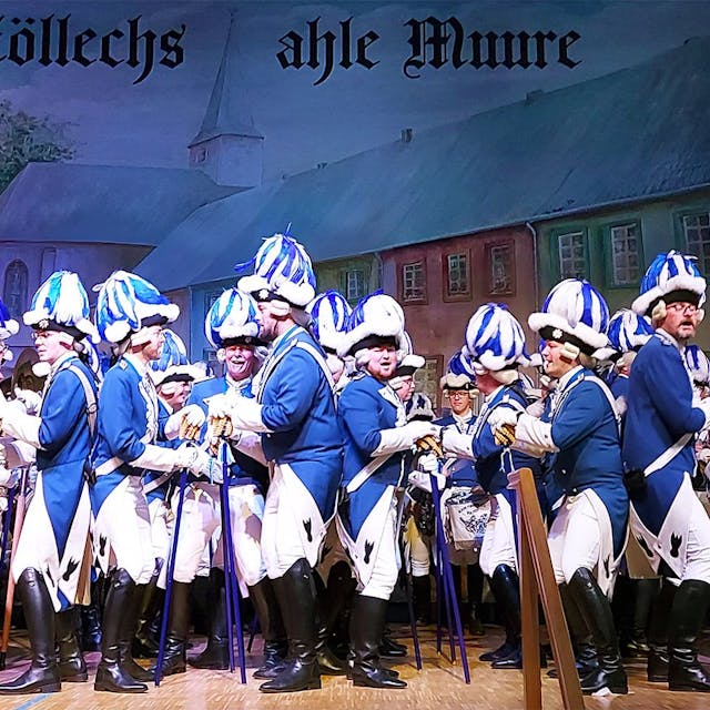 Die Blauen Funken bei ihrem Auftritt: Eine große Anzahl von uniformierten Männern steht Rücken an Rücken auf der Bühne beim Stippefötche.&nbsp;&nbsp;
