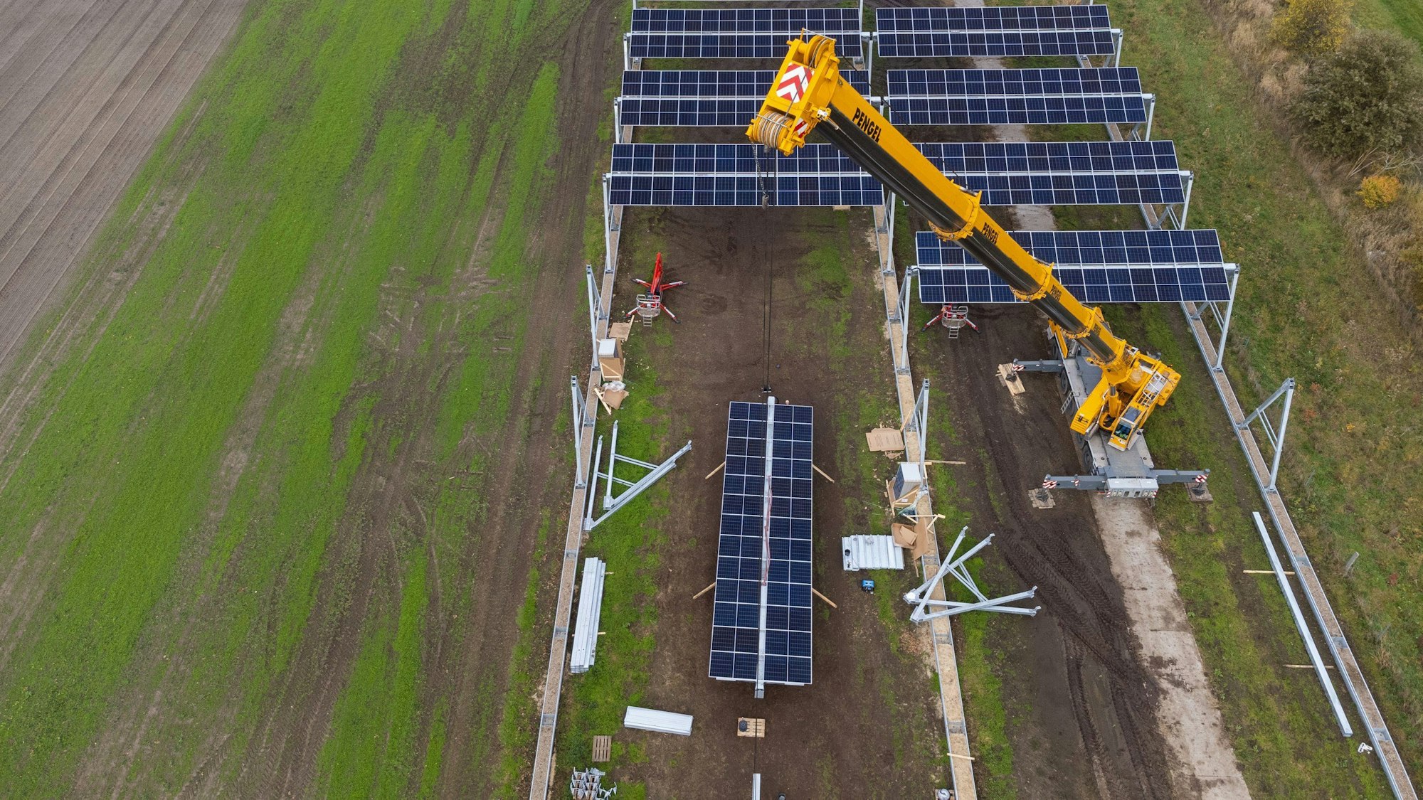 Mit einem Kran wird eine Agrar-Photovoltaik-Anlage montiert (die Aufnahme entstand mit einer Drohne). Im Wendland entsteht in einem Pilotprojekt die größte deutsche Agro-Photovoltaik-Anlage.