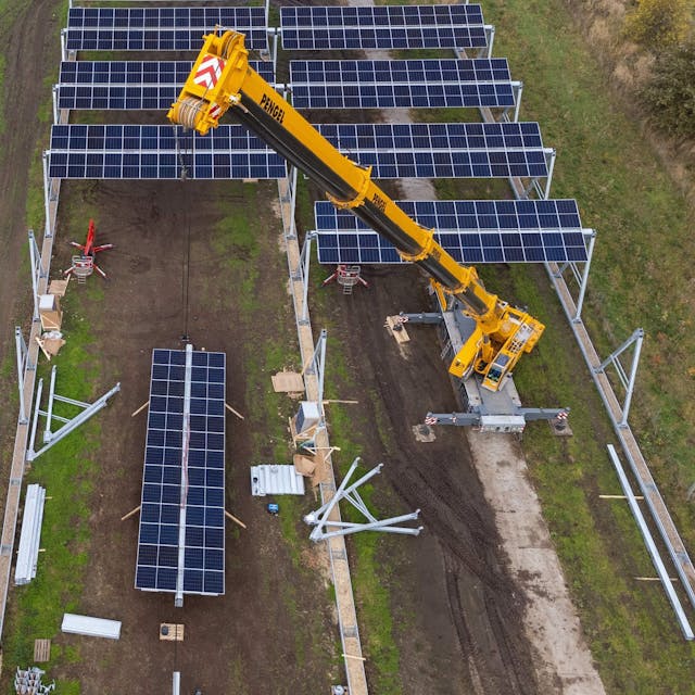 Mit einem Kran wird eine Agrar-Photovoltaik-Anlage montiert (die Aufnahme entstand mit einer Drohne). Im Wendland entsteht in einem Pilotprojekt die größte deutsche Agro-Photovoltaik-Anlage.&nbsp;