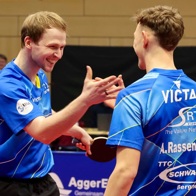 Die beiden Tischtennisspieler Benedikt Duda und Adrien Rassenfosse lachen und schlagen mit den Händen ein.