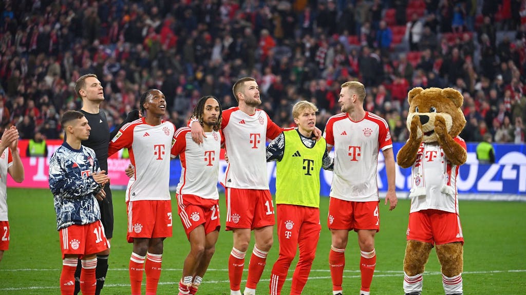 Die Bayern-Profis Bryan Zaragoza, Manuel Neuer, Mathys Tel, Sacha Boey, Eric Dier, Frans Krätzig und Eric Dier feiern gemeinsam mit Maskottchen Berni vor den Fans.