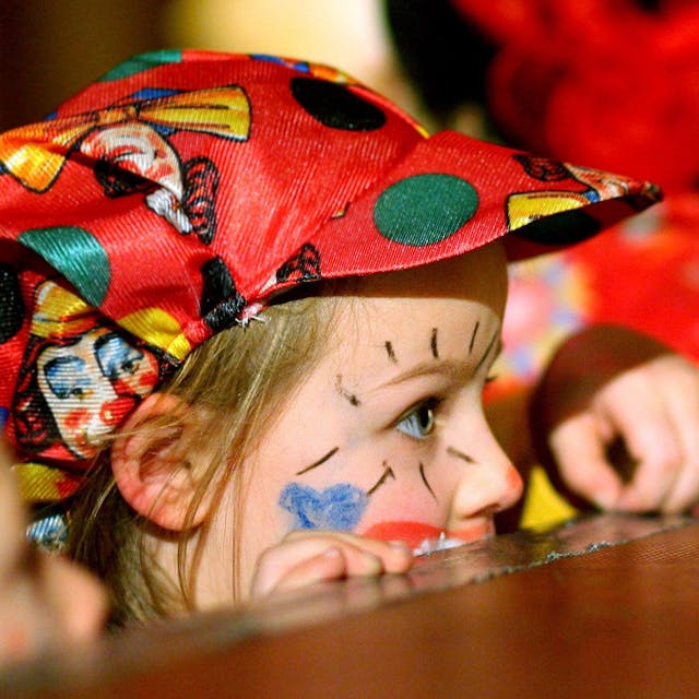 Zu sehen ist ein Kind im Clown-Kostüm auf einer Karnevalssitzung.&nbsp;