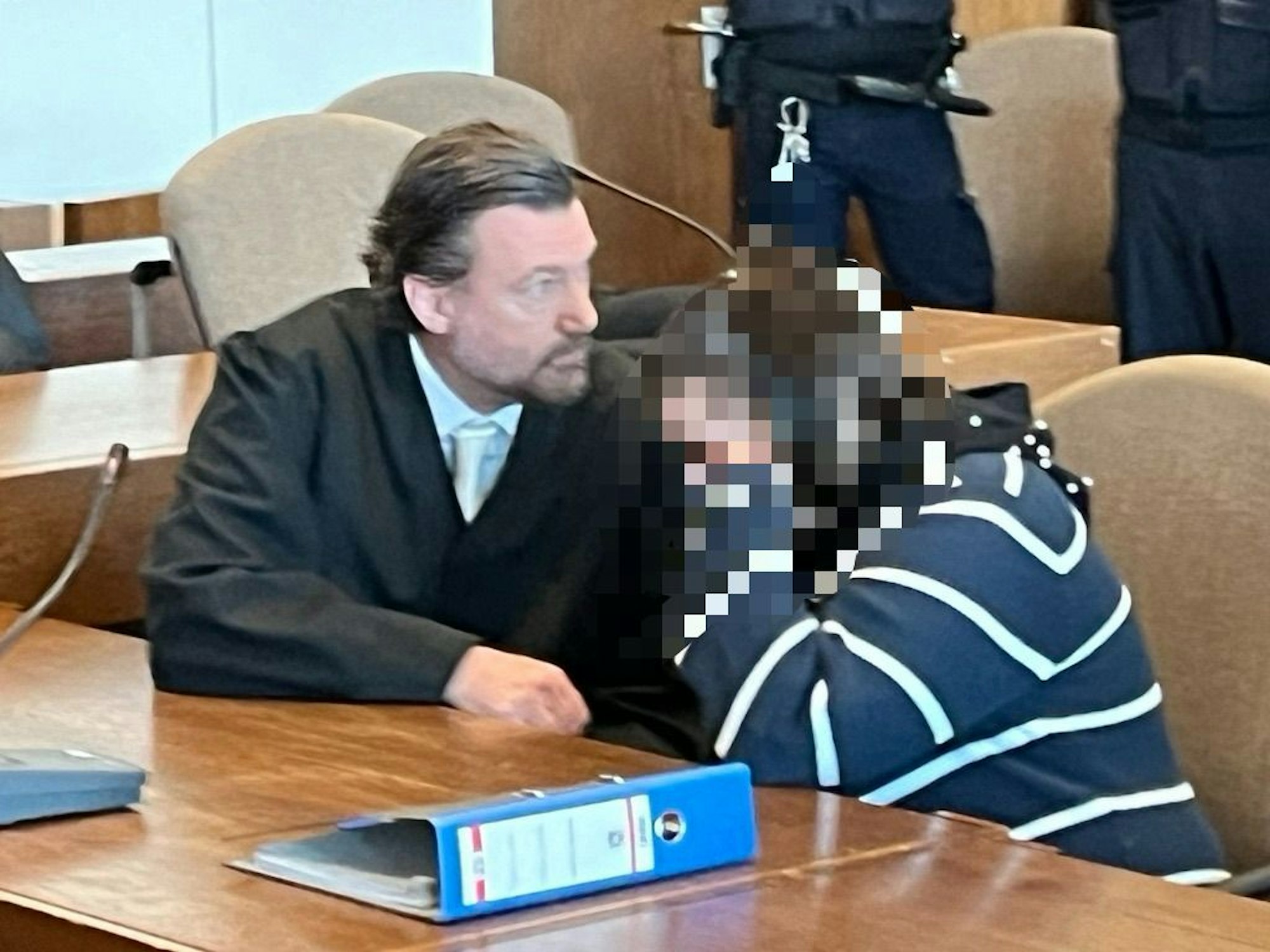 Eine Angeklagte versteckt sich neben ihrem Anwalt vor den Kameras.