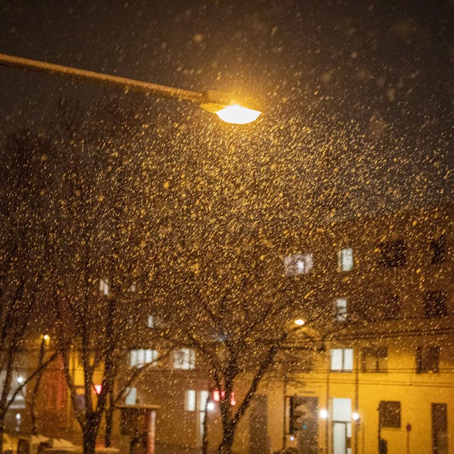 Das Schneetreiben in Köln ist im Licht einer Straßenlaterne zu sehen. (Symbolbild)