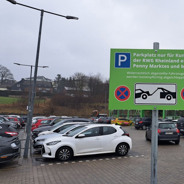 Das Foto zeigt den Parkplatz zwischen Raiffeisen- und Penny-Markt und ein Schild mit der Aufschrift "Parkplatz nur für Kunden".
