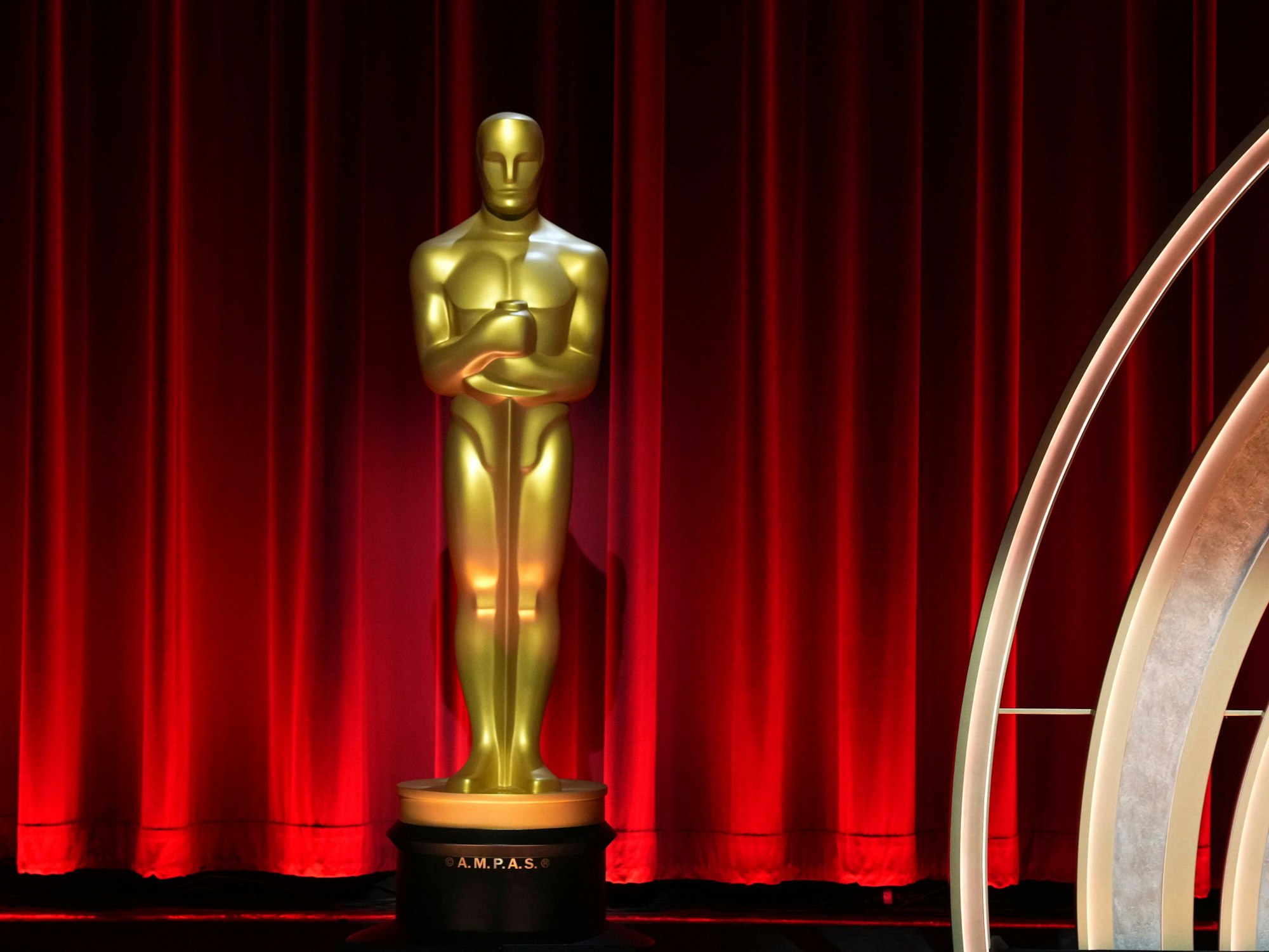 Eine Oscar-Figur steht vor einem roten Vorhang