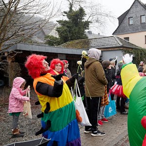 Bei einem Karnevalszug feiern zwei als bunte Clowns verkleidete Jecke in Schleiden.