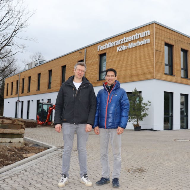 Zwei Männer stehen vor einem neuen zweistöckigen Gebäude mit der Aufschrift Fachtierarztzentrum Köln-Merheim.