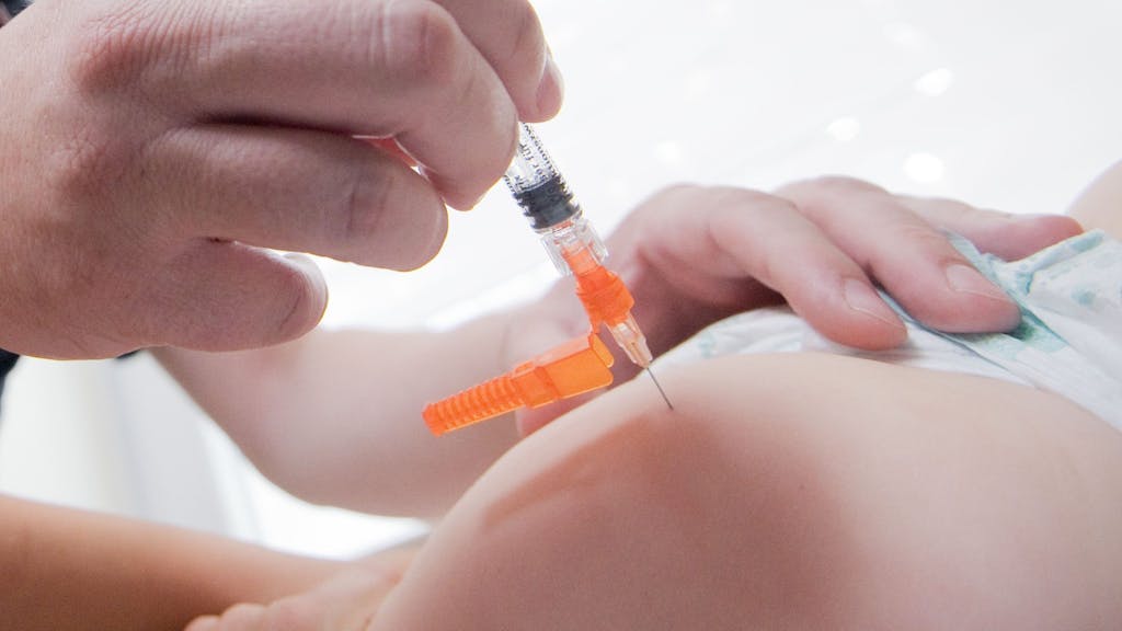 Ein Arzt injiziert einem Kind eine Masern-Impfung mit einer Spritze.
