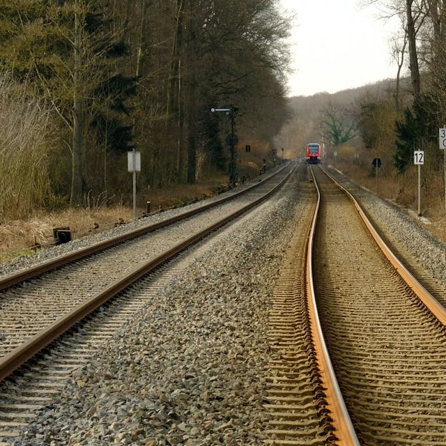 Ein zweigleisiger Abschnitt der Eifelstrecke bei Satzvey. Im Hintergrund ist ein sich nähernder Zug zu erkennen.