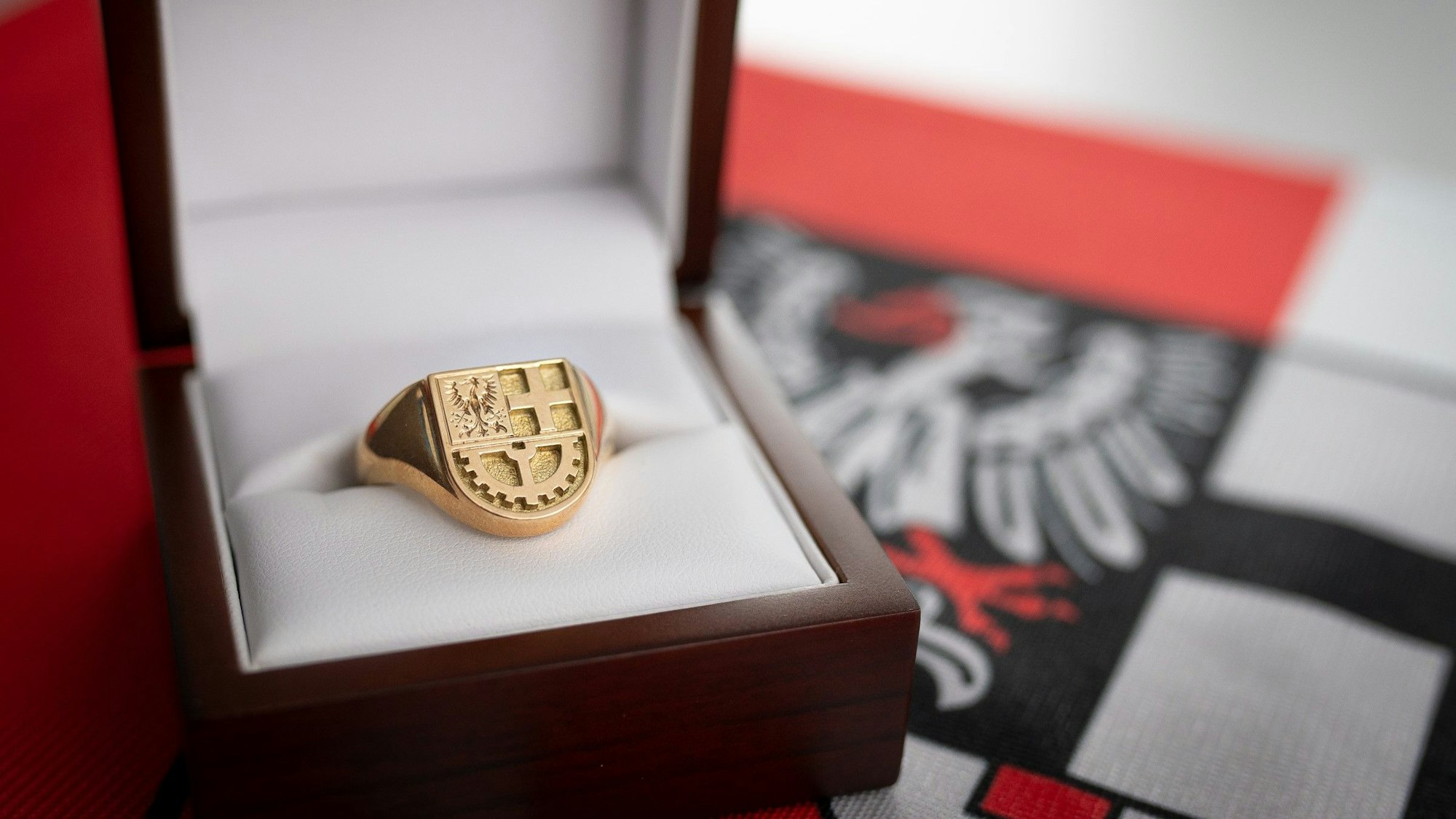 Ein goldener Ring mit Wappen in einer Schmuckschatulle.
