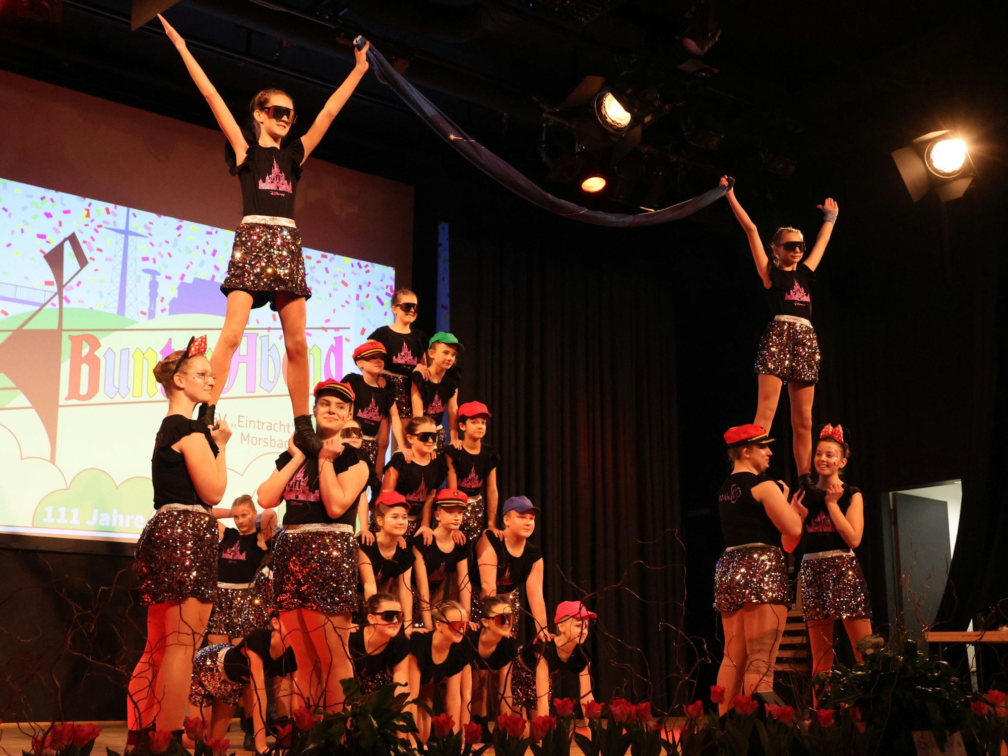 Mehrere Mädchen einer Tanzgruppe bilden bei einem Auftritt auf einer Bühne eine Pyramide.