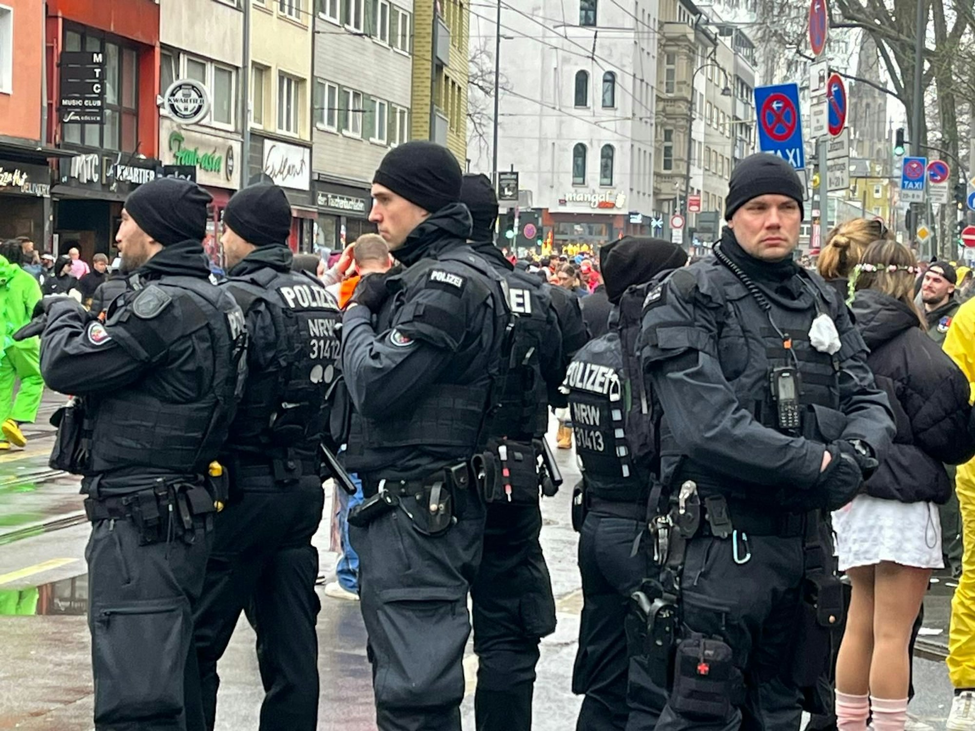 Eine Gruppe von Polizisten steht zwischen feiernden Menschen.