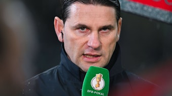 Trainer von Borussia Mönchengladbach spricht in ein Mikrofon.