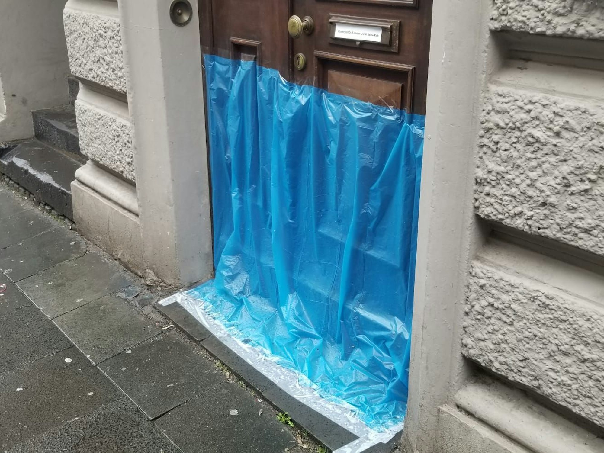 Eine Plastikplane ist an einer Haustür angebracht.
