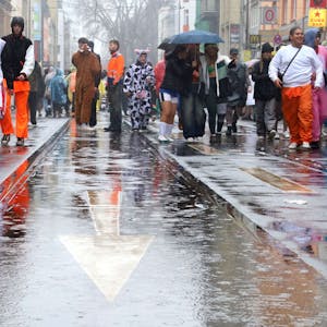 Kostümierte gehen über die nasse Zülpicher Straße.
