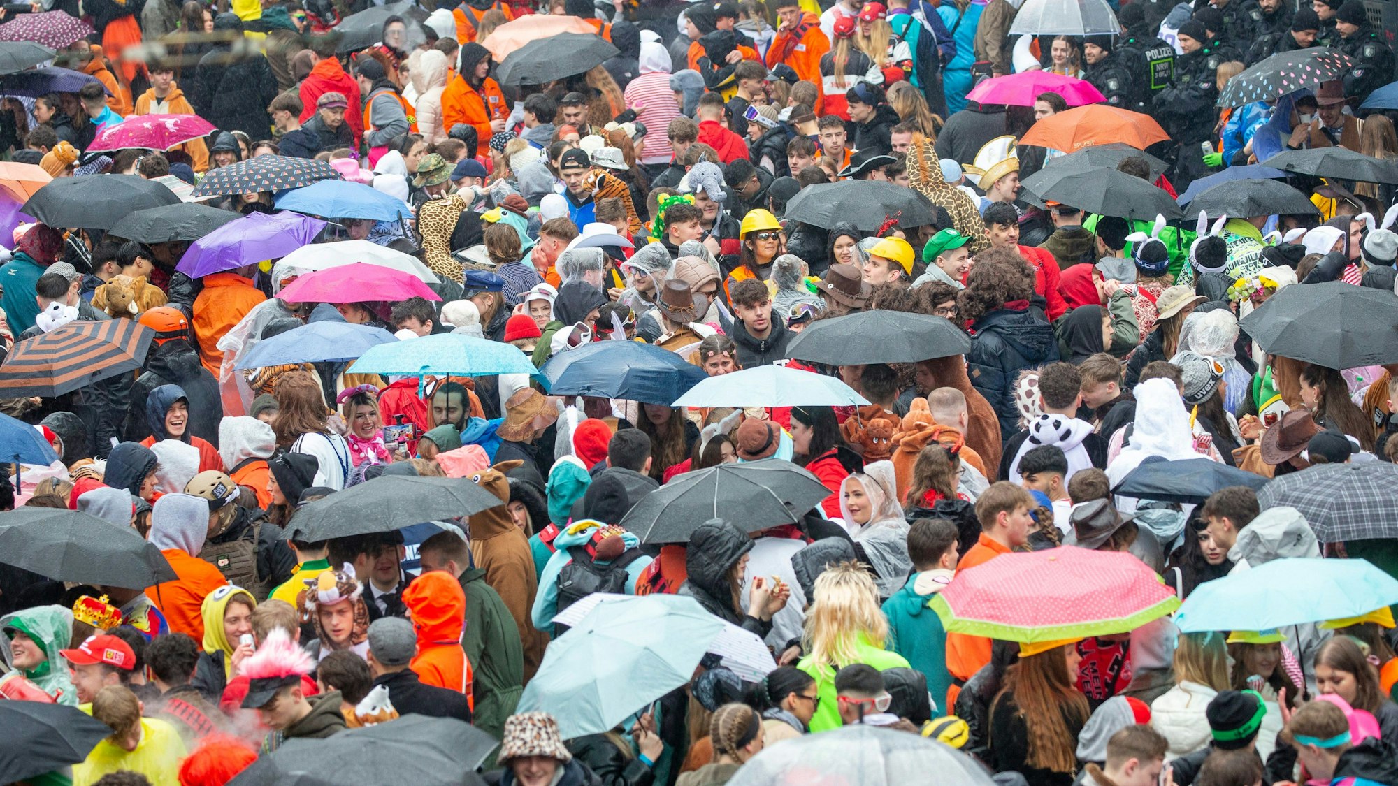 Gegen 11 Uhr wird der Regen wieder stärker. Die Leute drängen sich gemeinsam unter Regenschirme.