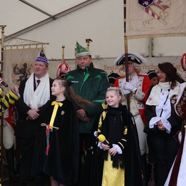 Auf dem Bild ist Frechens Bürgermeisterin und die beiden Prinzessinnen zu sehen. Hinter ihnen stehen viele karnevalistisch verkleidete Personen.