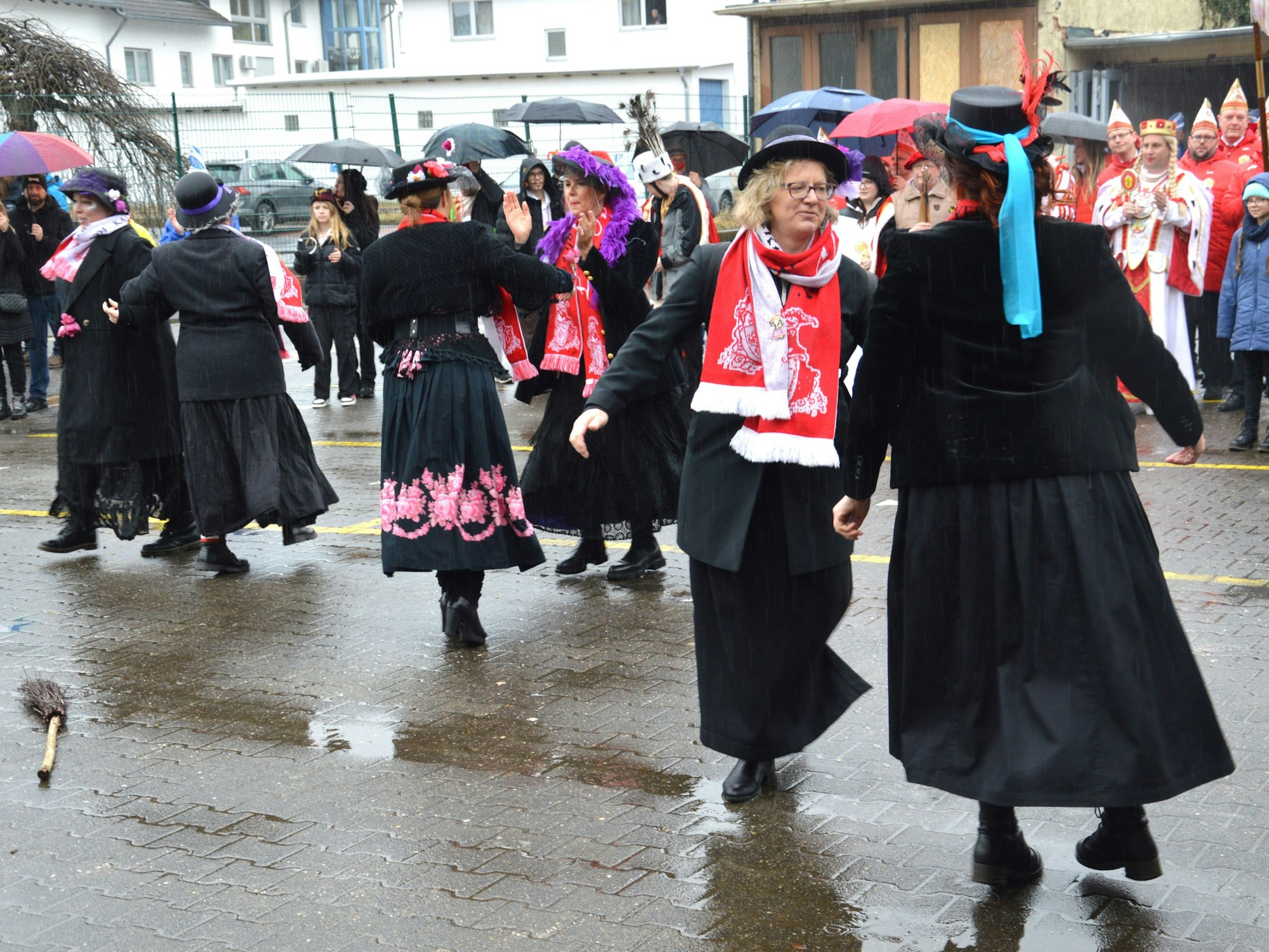 In schwarzen Kleidern und mit bunten Schals gekleidete Frauen tanzen.
