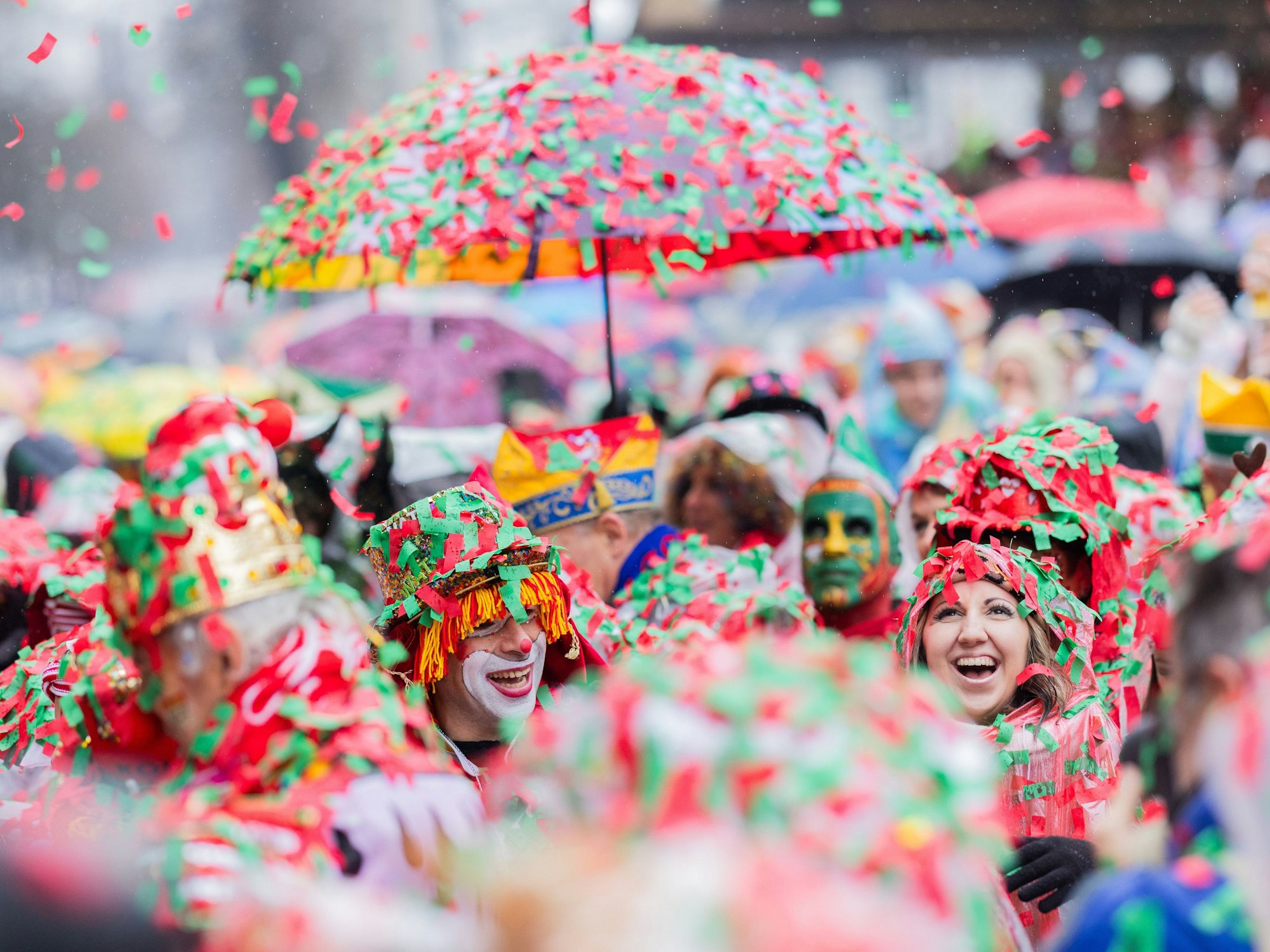 Karnevalisten sind komplett mit nassem Konfetti bedeckt und feiern an Weiberfastnacht die Eröffnung des Straßenkarnevals auf dem Alter Markt.