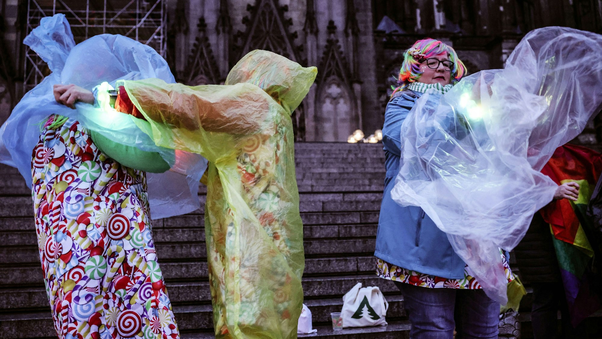 Karnevalisten ziehen sich am Dom einen Regenschutz über das Kostüm.