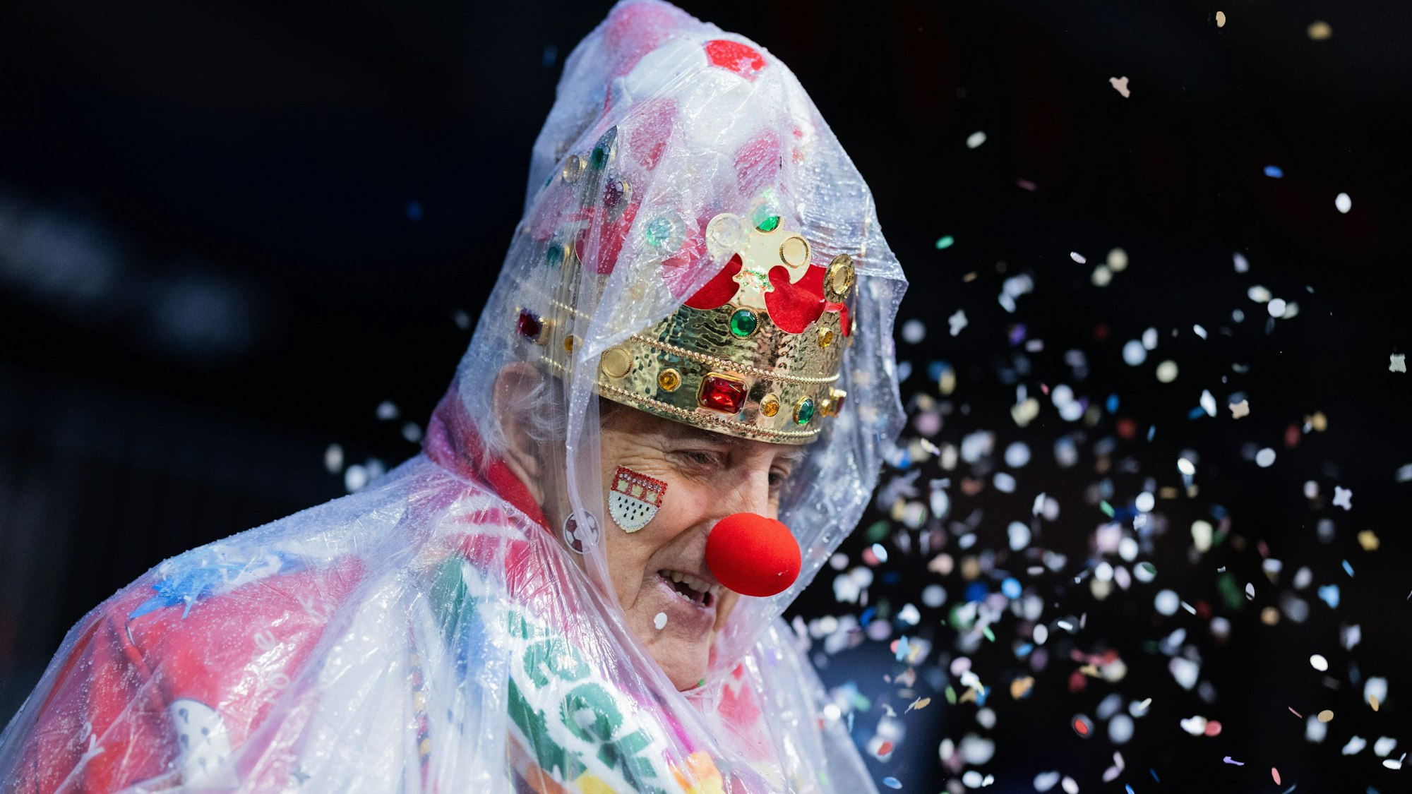 Ein Karnevalist mit Regenschutz wartet an Weiberfastnacht auf die Eröffnung des Straßenkarnevals auf dem Alter Markt.
