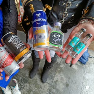 Zwei junge Menschen halten verschiedene alkoholische Getränke in den Händen.