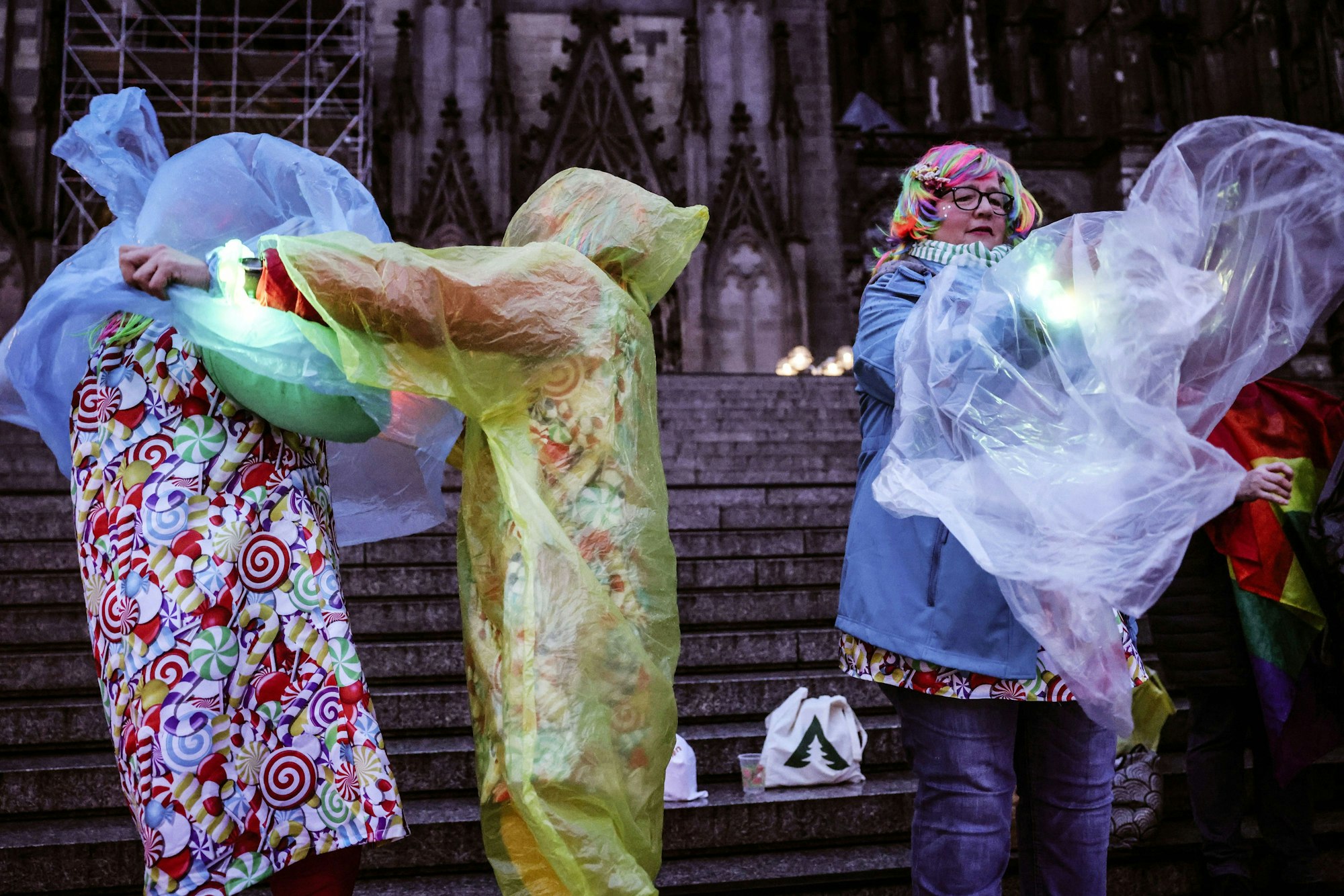 Karnevalisten ziehen sich am Dom einen Regenschutz über das Kostüm.