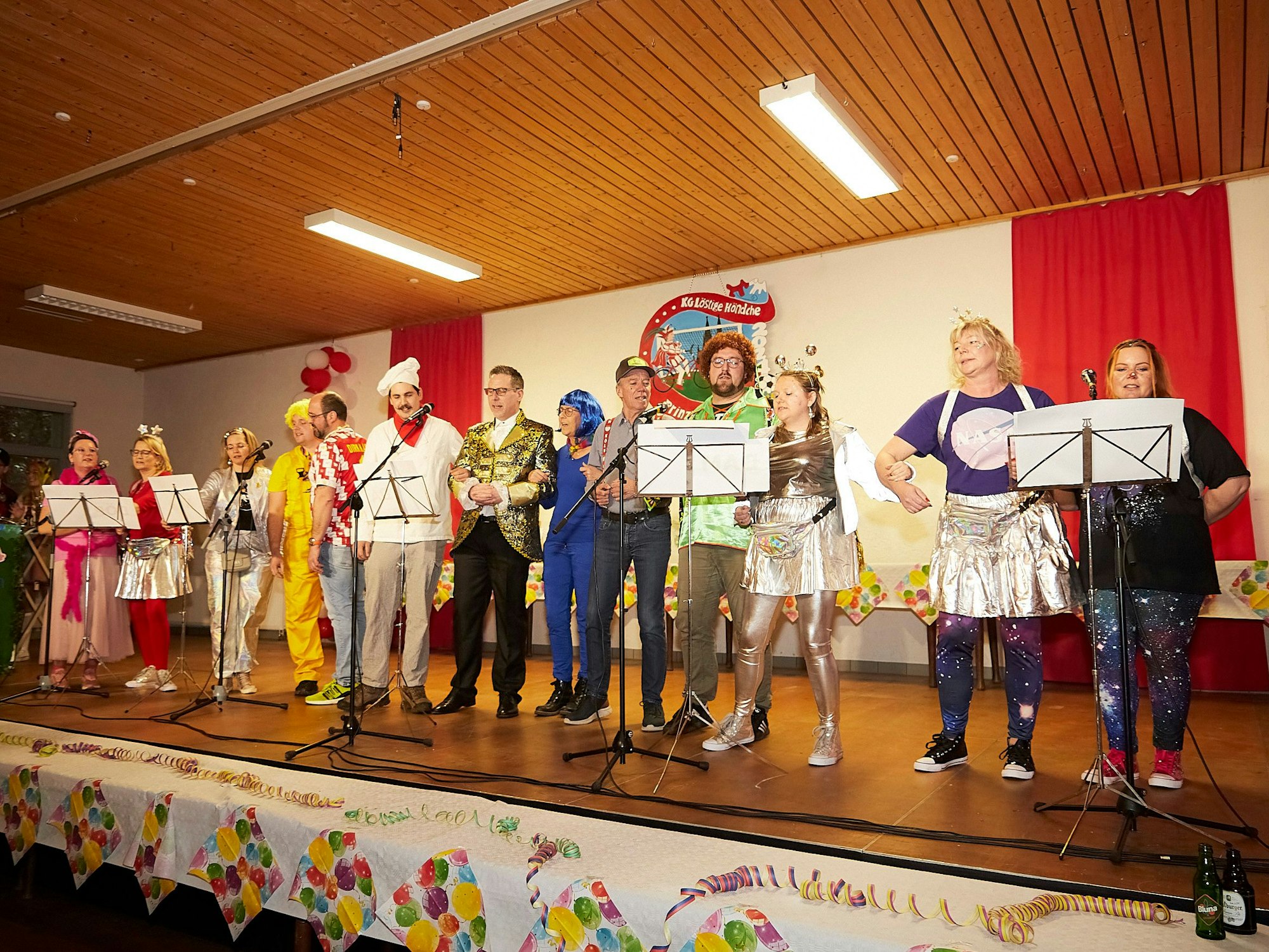 Mit ehemaligen Mitgliedern und Bürgermeister sangen die „Rathausschwalben“, die Gesangsgruppe der Nettersheimer Verwaltung. Sie stehen verkleidet nebeneinander auf der Bühne.