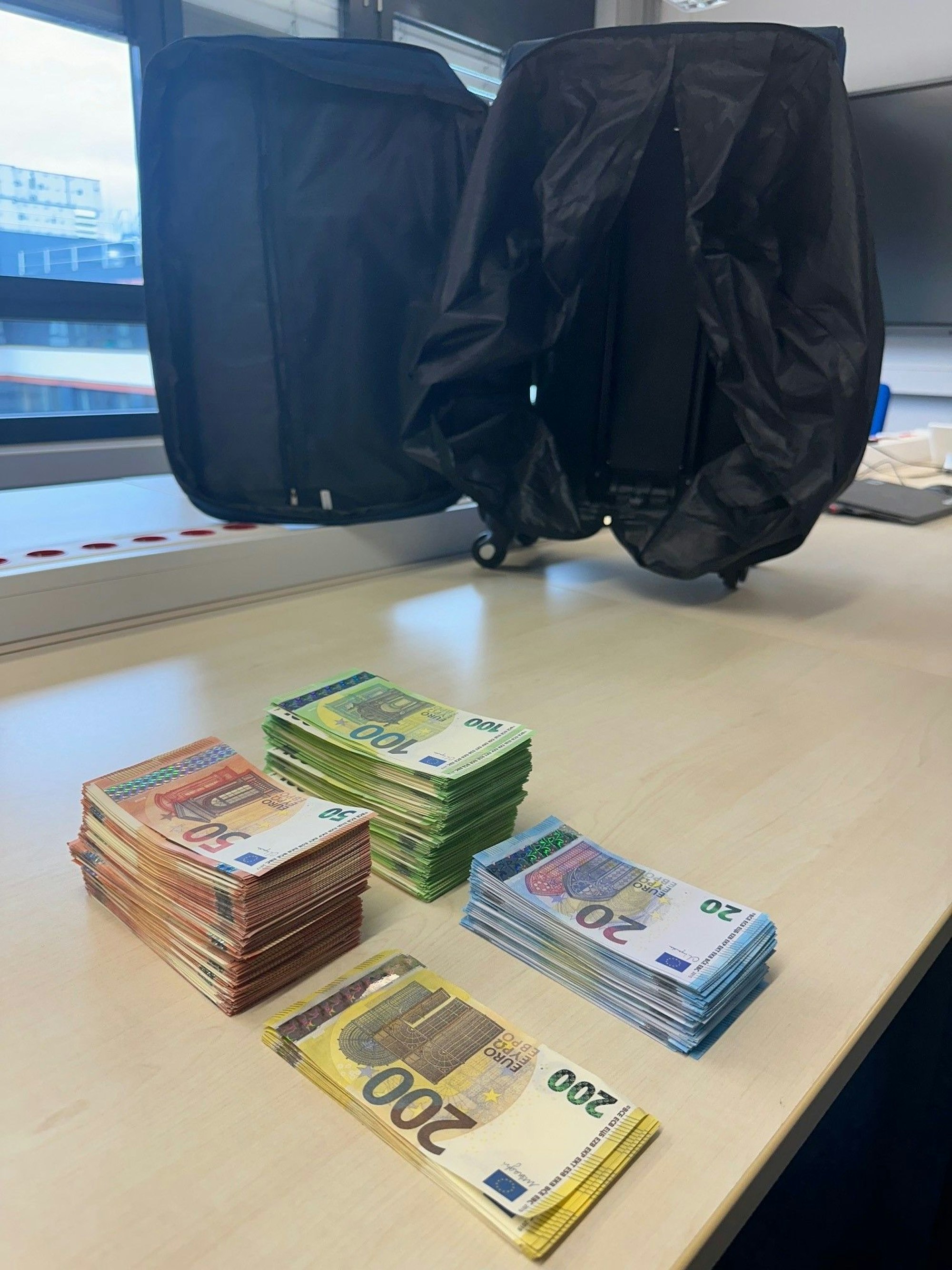 Gefälschte Geldscheine liegen auf einem Tisch im Polizeipräsidium Köln, daneben steht ein Koffer.