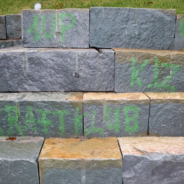 Das Bild zeigt die geschmierten Aufschriften mit den Bandnamen „Kraftklub“ und „K.I.Z“ auf den Natursteinen.