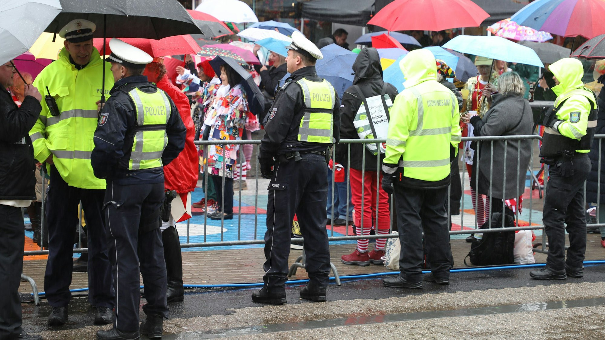 Polizeibeamte und Mitarbeitende des Ordnungsamts stehen beim Rathaussturm in Bensberg an einer Absperrung.